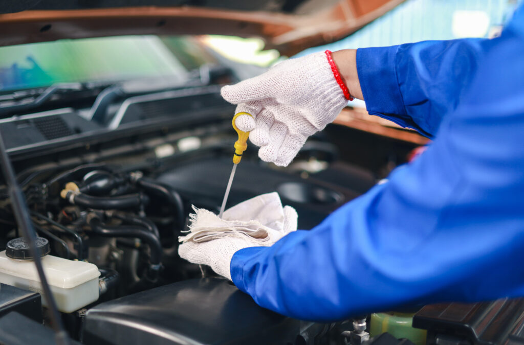 Close-up of a car mechanic checking the engine oil.