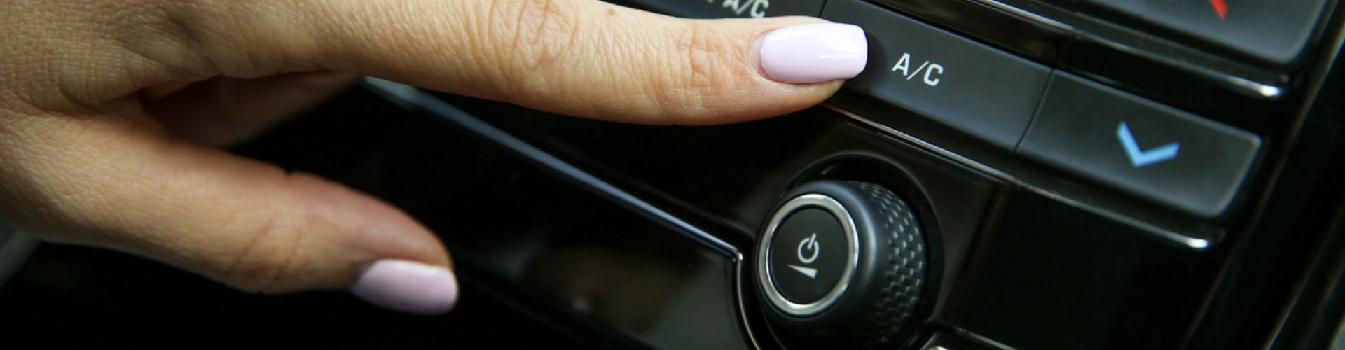 A close-up of a person with painted nails turning the A/C on in a BMW.