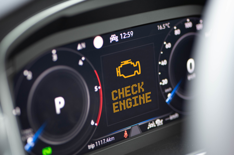 Interior of a modern BMW and a flashing check engine warning light on the dashboard.