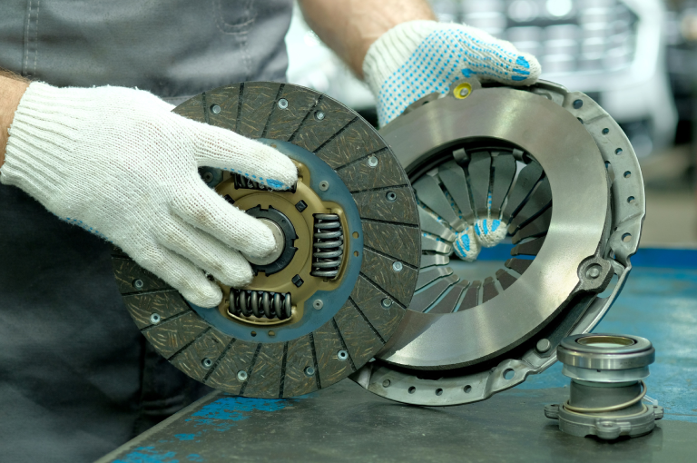 A mechanic with a new drive disc and exhaust bearing for a BMW.