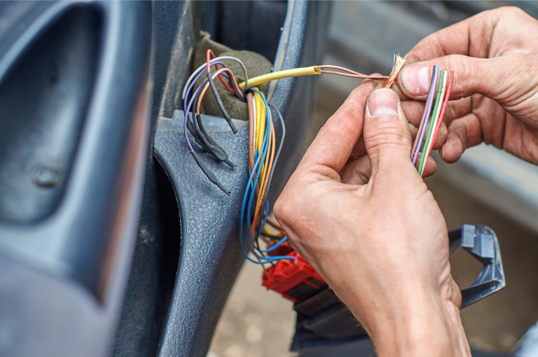Close-up of an auto mechanic’s hands connecting electrical cables in a BMW car door.