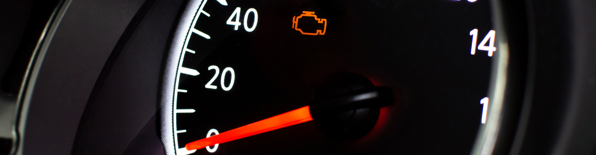 A close-up of a BMW’s speedometer with an illuminated orange check engine light.