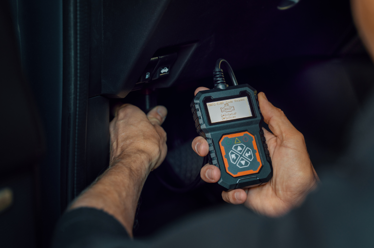 An auto mechanic using an OBD2 scanner to run diagnostics on the check engine light in a BMW.