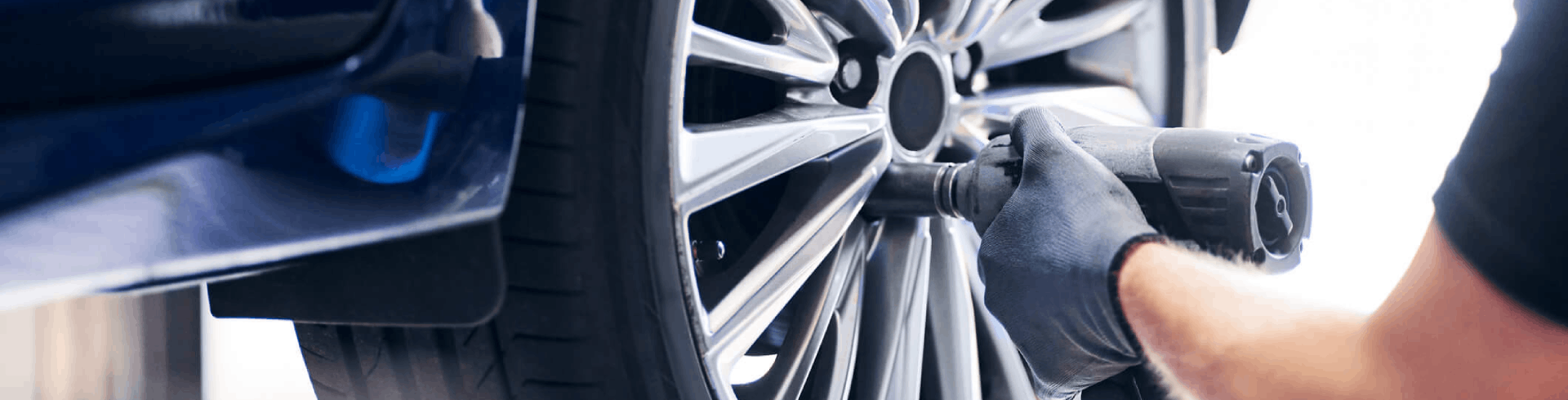 Mechanic changing car wheel in auto service using pneumatic wrench