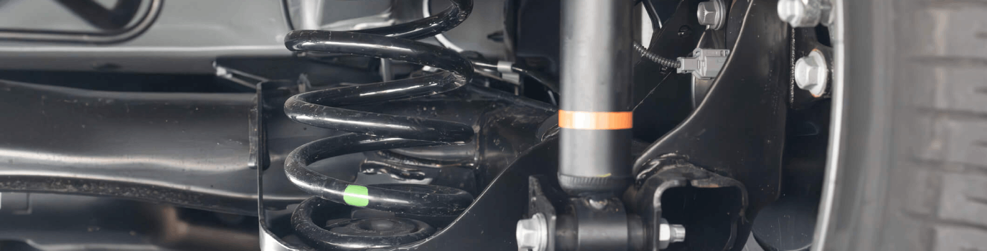 View from under a car of its suspension and rear drive shaft.