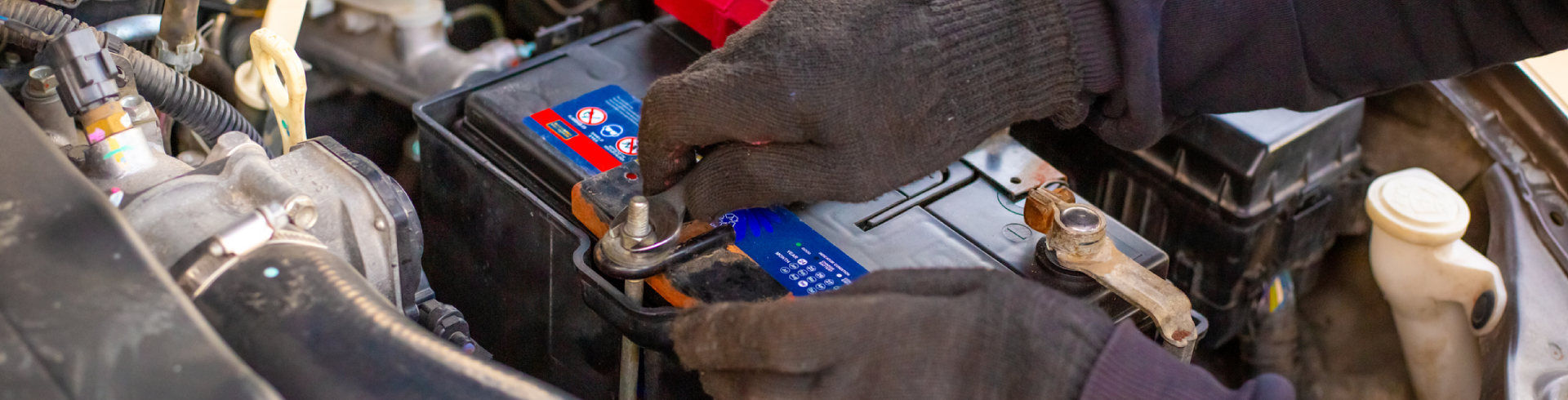 Auto technician replaces Audi battery using a small wrench.