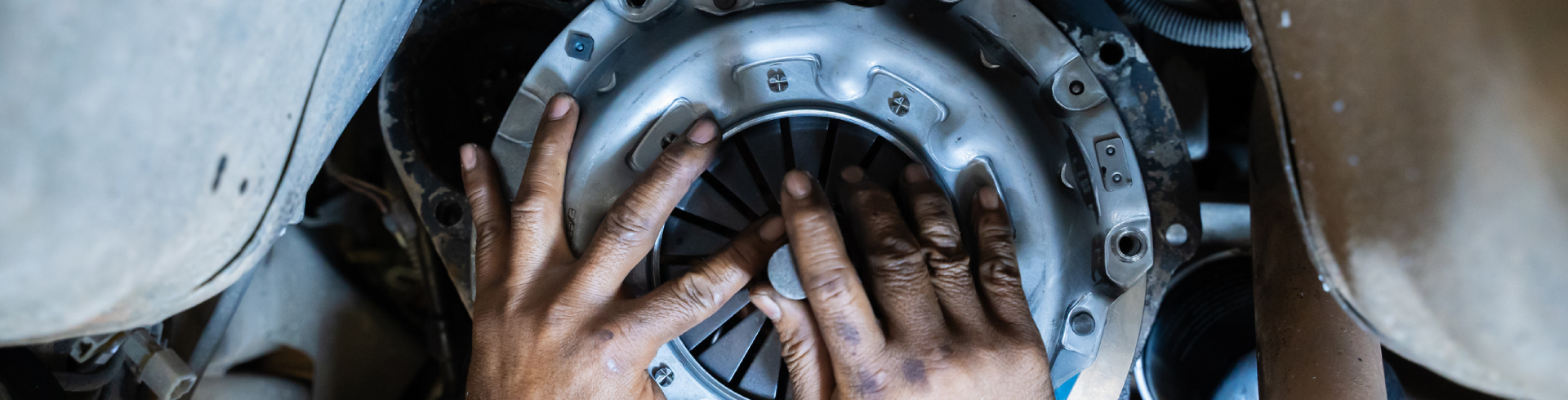 Auto technician repairs Audi clutch in auto shop with his hands.