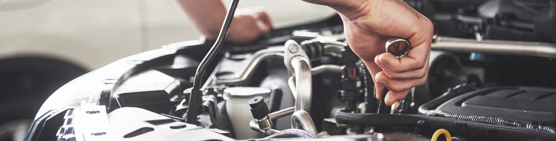 Close up, a mechanic is repairing Audi engine using a metal tool.