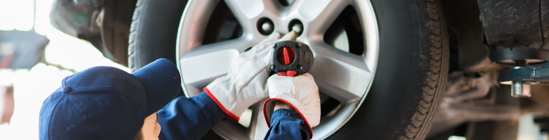Mechanic putting new tires on Audi in an auto shop.