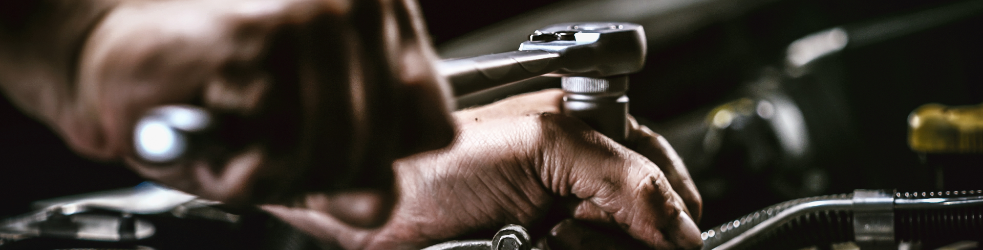 Close up of mechanic’s hands. They are repairing Audi transmission using a wrench.