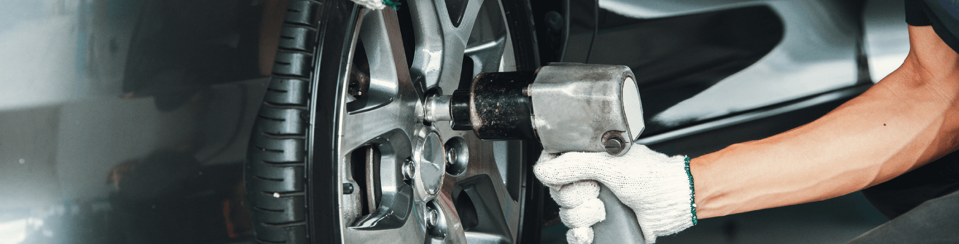 Close-up, mechanic wearing white gloves performing a tire replacement for Mercedes vehicle.