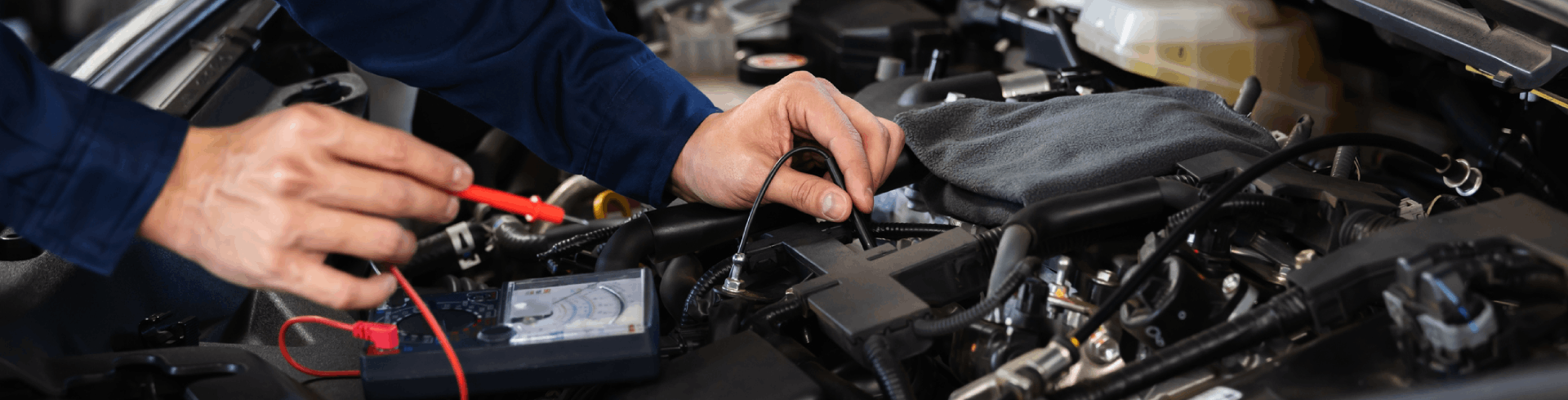 A mechanic hand-checks a MINI Cooper’s electrical wiring system.