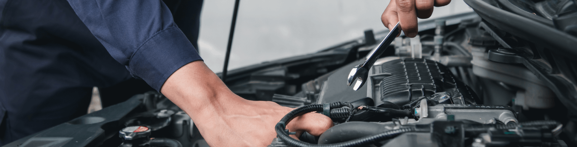 Mechanic using wrench while working on Mercedes engine.