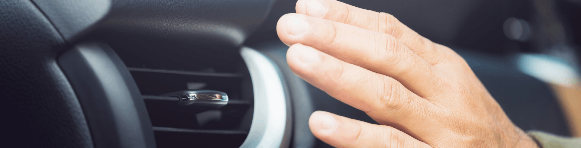 Car owner checks the air conditioning system by feeling the cool air from the vent.