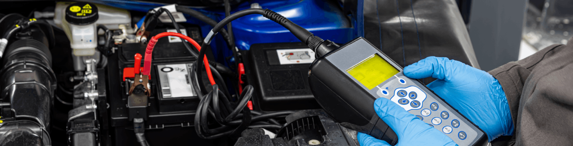 Mechanic inspecting Mercedes car battery using a digital device.
