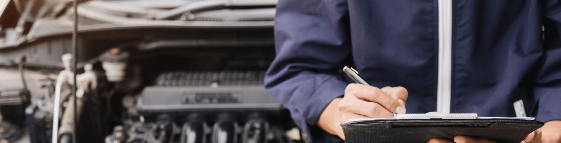 A mechanic performs Mercedes pre-purchase inspection, checking the engine and taking notes on a clip board with a pen.