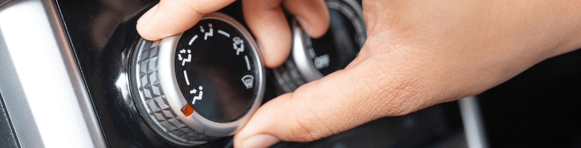 A person adjusts a car’s AC, turning the control nob all the way to the left.