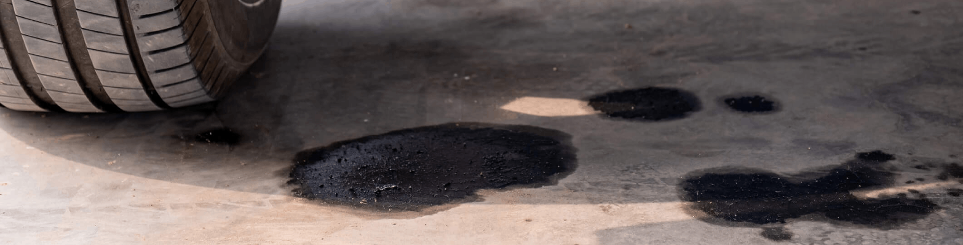 Close-up of oil leaking from a car onto a concrete floor