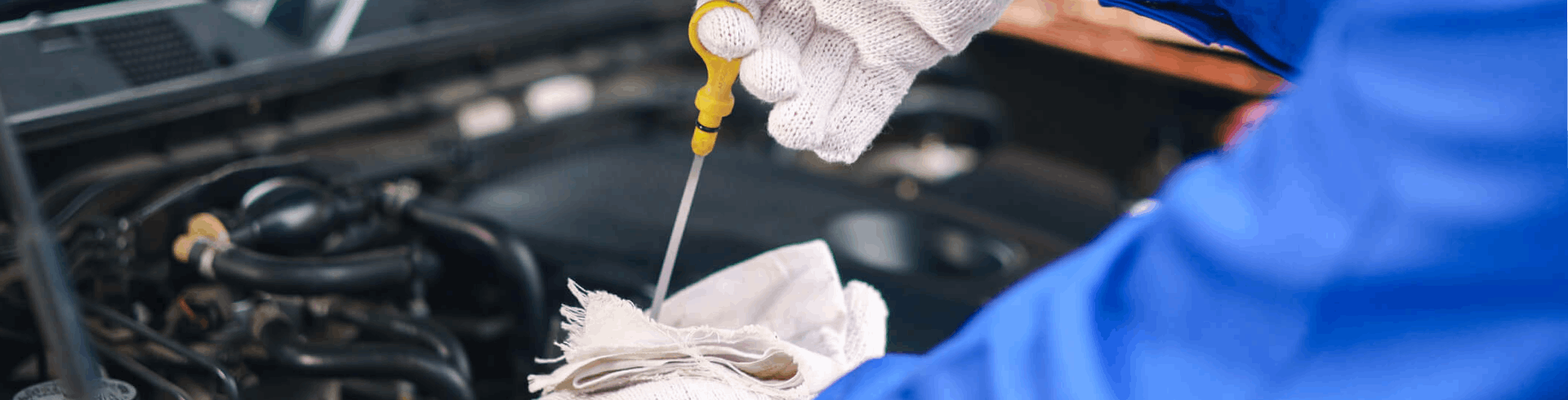 Close-up of a car mechanic checking the engine oil.