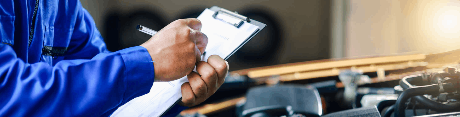 Mechanic with a clipboard and a pen checking under the hood of a vehicle during a pre-purchase inspection.