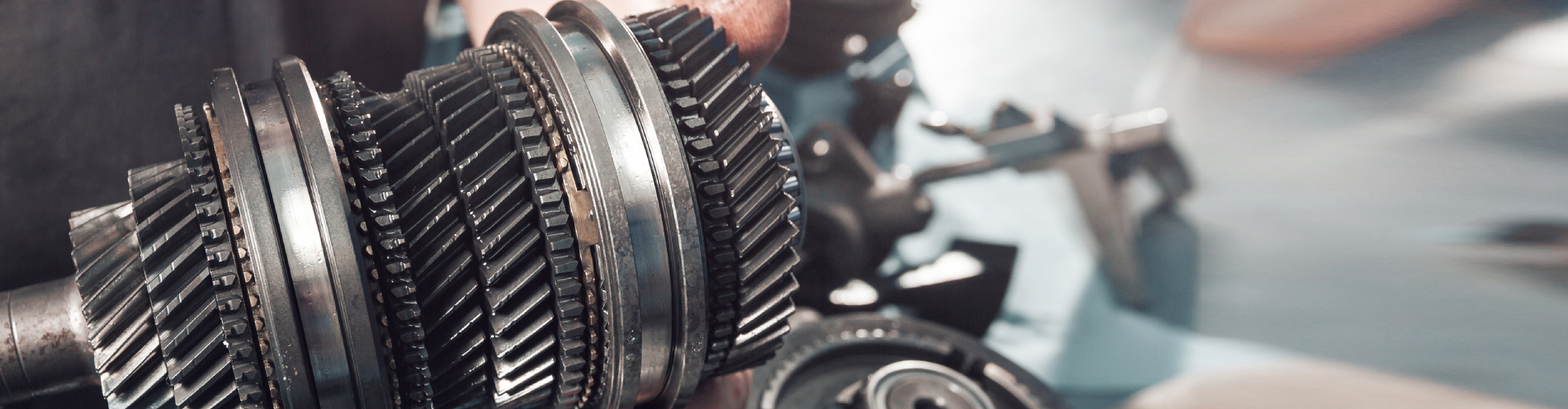 Mechanic holds up a vehicle’s gearbox, close-up shot of transmission repair.