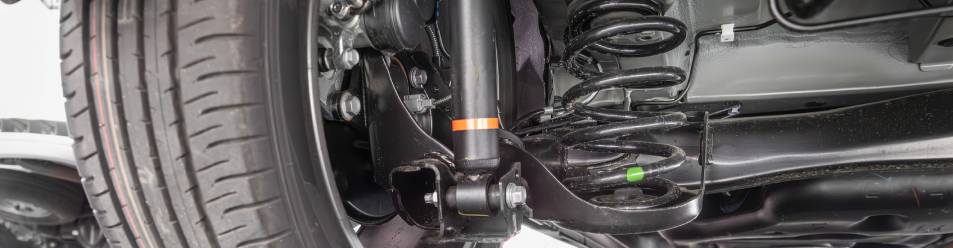Close up view of vehicle’s suspension and rear drive shaft from under the car.