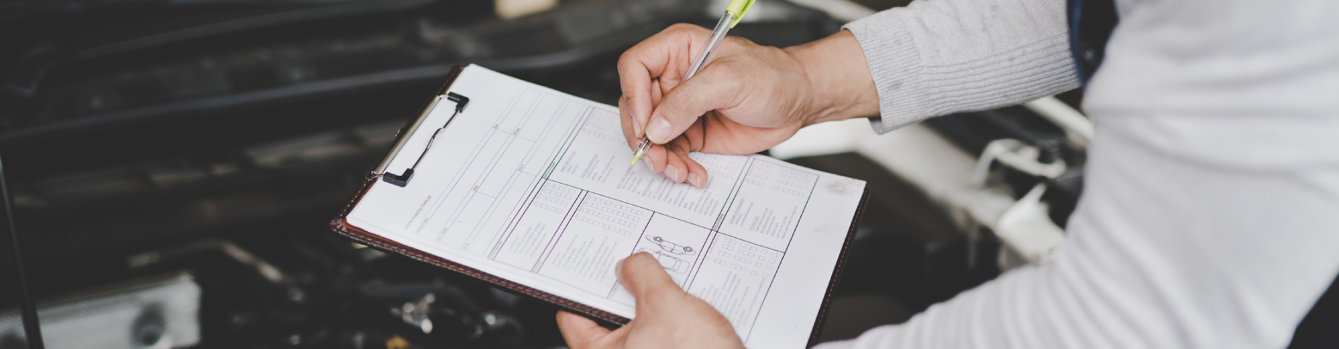 Mechanic with a checklist on a clipboard performs a pre-purchase inspection.