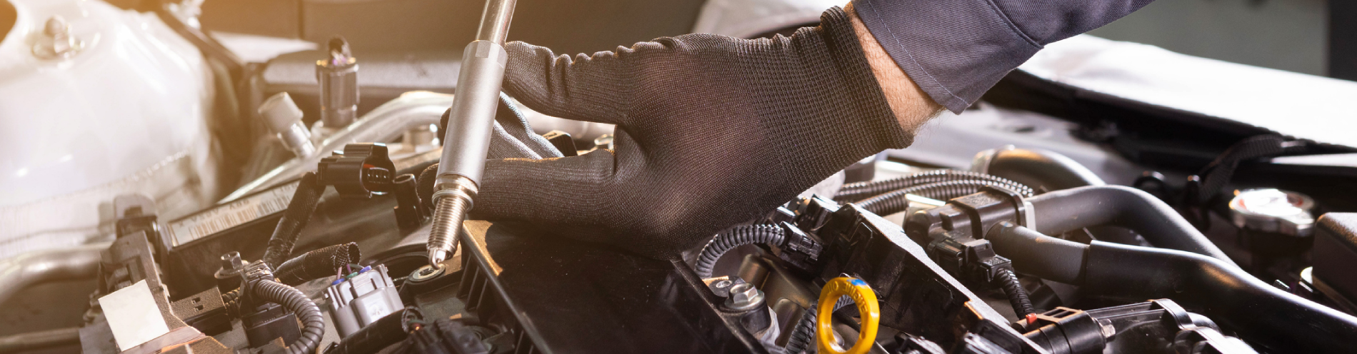 Mechanic performs routine car diagnostics using a long metal tool. They’re working on the car’s engine.