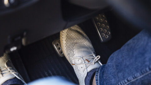Close-up of driver's feet pressing the brake pedal in car