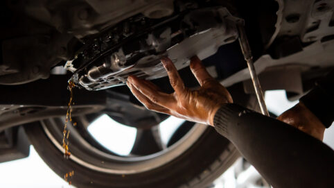 Car mechanic drain the old automatic transmission fluid (ATF) or gear oil at car garage for changing the oil in a gear box of car engine