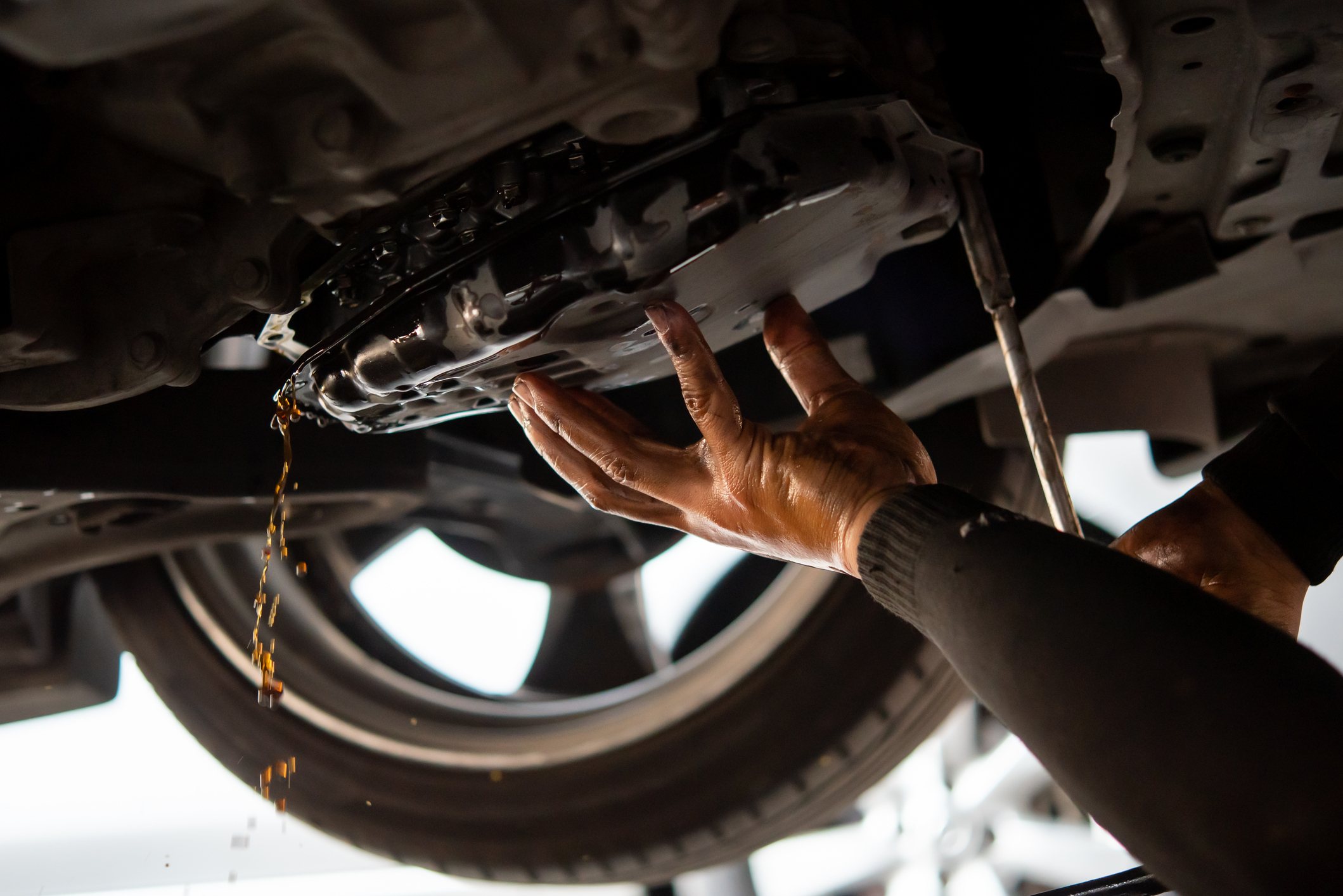 Car mechanic drain the old automatic transmission fluid (ATF) or gear oil at car garage for changing the oil in a gear box of car engine